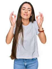 Wall Mural - Young hispanic girl wearing casual white t shirt relaxed and smiling with eyes closed doing meditation gesture with fingers. yoga concept.