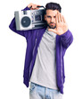 © Krakenimages.com - Young handsome man with beard listening to music using vintage boombox with open hand doing stop sign with serious and confident expression, defense gesture