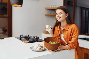 Canvas Print - Young woman enjoying a fresh salad in a modern kitchen, showcasing healthy eating habits and a cheerful atmosphere