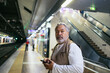 © Pedro Merino/Stocksy - Senior man using smartphone while waiting for the subway