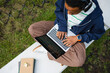 © DZ FILM/Stocksy - A man uses a laptop while sitting outdoors