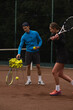 © Oleksandr Stalovierov/Stocksy - Man teaching girl how to play tennis on court.