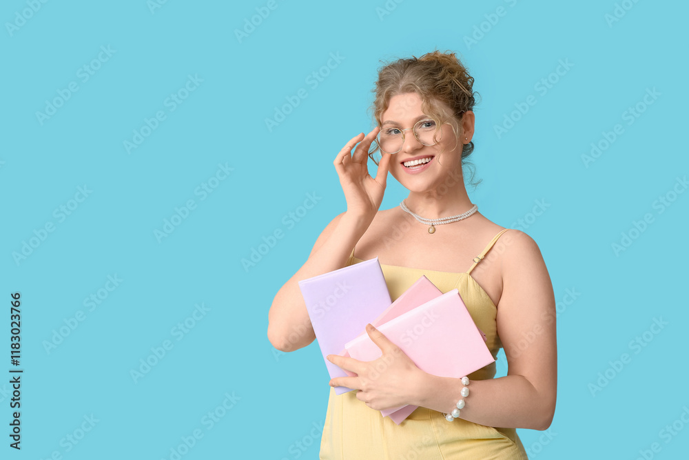 Beautiful young happy woman with notebooks on blue background