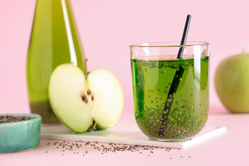 Wall Mural - Bottle and glass of lemonade with chia seeds and apple on pink background