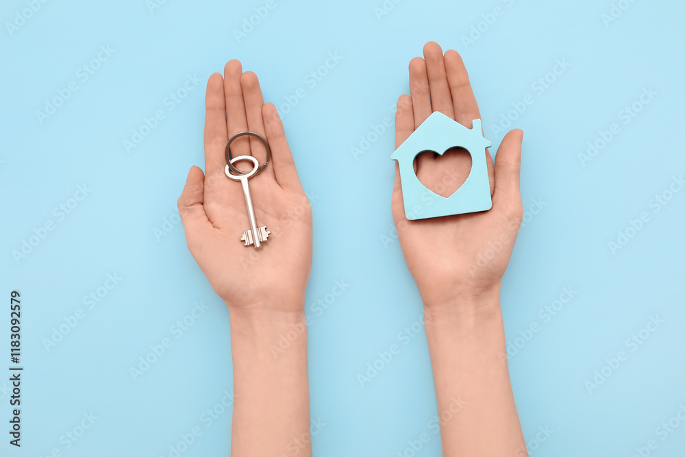 Female hands with key and house figure on blue background