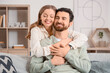© Pixel-Shot - Apologizing young woman hugging her husband on sofa at home