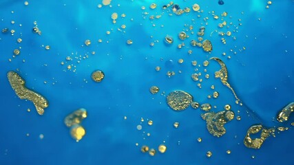 Poster - Dynamic drops of yellow glitter in blue oil or ink diffusing through water, creating an abstract aquatic swirls