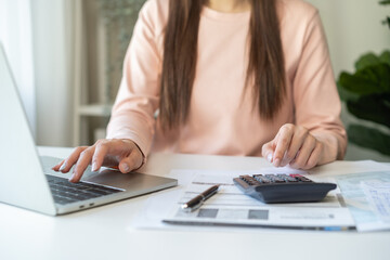 Wall Mural - Deduction planning, debt asian young woman  hand using laptop computer, calculator calculating money balance from bill and income, cost budget expenses for pay money form personal individual on table.