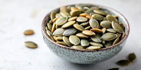 Aufkleber - Pumpkin seeds are arranged in a small bowl on a white table, showcasing a healthy snack option. This pumpkin seeds image emphasizes a diet concept with copy space and selective focus.