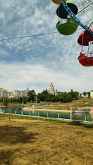 Wall Mural - Saransk, Russia - July 14, 2024: Cathedral of the Holy Righteous Warrior Feodor Ushakov. Ferris Wheel attraction. A.S. Pushkin Park of Culture and Recreation. Republic of Mordovia