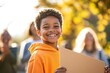 © Larisa - Smiling boy in orange hoodie at sunset with placard