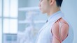 © Thanawat - A medical professional stands with a muscular arm model, emphasizing anatomy and education in a clinical environment.