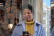 © Cavan Images - Woman using smartphone standing next to a shop window in the city