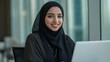 © Vadim - Focused young middle eastern businesswoman smiling while working on her laptop computer