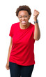© Krakenimages.com - Beautiful young african american woman wearing glasses over isolated background angry and mad raising fist frustrated and furious while shouting with anger. Rage and aggressive concept.