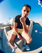 © Studio Marmellata - A young man in yellow shorts and white sneakers poses confidently on a concrete urban ledge captured under bright sunlight and a vivid blue sky using a fisheye lens perspective