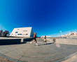 © Studio Marmellata - Two men, one in red and one in black, are jogging near a modern urban architectural building under a vibrant blue sky on a sunny day, enjoying the outdoors in a contemporary environment