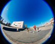 © Studio Marmellata - Two men, one in red and one in black, are jogging near a modern urban architectural building under a vibrant blue sky on a sunny day, enjoying the outdoors in a contemporary environment