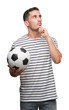 © Krakenimages.com - Handsome young man holding soccer football serious face thinking about question, very confused idea
