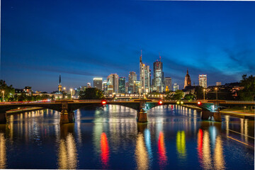 Wall Mural - Skyline view from a bridge. Metropolis with skyscrapers reflected in a river. City of Frankfurt am Main, Germany