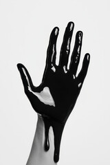 Poster - Minimalistic Black and White Photo of a Hand Covered in Black Oil on White Background