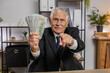 © Andrii Iemelianenko - Rich old grandfather businessman freelancer working at home office workplace counting money dollar cash, calculate earnings income profit pointing at camera. Business people. Employment occupation