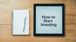 © auc - Investment research guide concept. How to start investing on a digital tablet with a notebook and pen.
