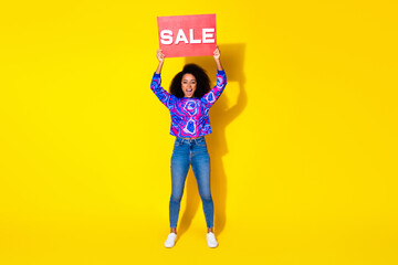 Wall Mural - Full body photo of attractive young woman raise hold sale poster dressed stylish colorful blue clothes isolated on yellow color background