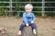 © Austockphoto - Portrait of little toddler boy sitting in garden with relaxed expression
