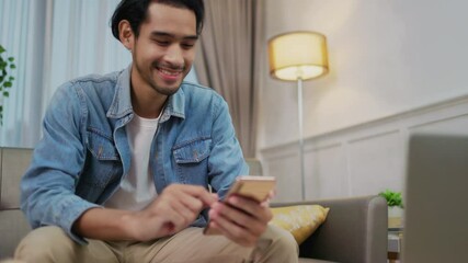 young adult asian man work at home or modern office, using desktop computer and smartphone. work fro