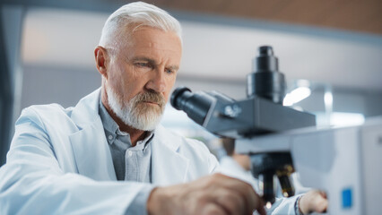 Poster - Senior Medical Research Scientist Looking at Biological Samples Under a Microscope in an Applied Science Laboratory. Portrait of a Handsome Middle Aged Doctor Working on a Research Project
