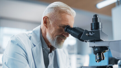 Wall Mural - Medical Research and Development Laboratory: Middle Aged Head Scientist Working on Research Project, Looking at a Biological Sample Under a Microscope in an Advanced Biotechnology Lab