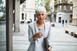 © Davor - Senior professional businesswoman using smartphone downtown