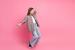 © deagreez - Young cheerful girl in trendy plaid shirt posing against a pink background with outstretched arms.