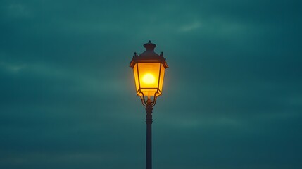 Vintage street lamp glows warmly against deep blue twilight sky, its curved form creating moody ambiance in minimalist urban nightscape with noir aesthetics.