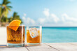© Quality One   - Refreshing cocktails on beach table with ice and orange garnish, perfect for sunny day by ocean. Enjoy tropical vibes and relaxation