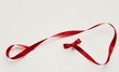 © Pixel Diversity - Red ribbon, single strand, curled, bow, white background, minimalist, elegant, festive, silk texture, bright crimson, gift wrapping, holiday decoration, smooth surface, soft shadows, simple compositio