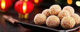 Sweet sesame balls on a plate, surrounded by festive decorations, showcasing a traditional dessert in a warm, inviting ambiance.