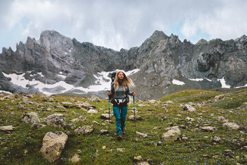 woman climbing mountains with trekking poles and backpack gear travel adventure lifestyle hiking sol