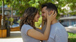 © Krakenimages.com - Woman embracing man while smiling in an urban park under the sun, conveying love and happiness outdoors.