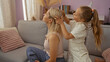© Krakenimages.com - Mother and daughter sitting together in a cozy living room as the child gently combs the woman's blonde hair