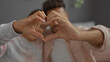© Krakenimages.com - Couple forming heart shape with their hands symbolizing love and togetherness while sitting indoors in a cozy home setting
