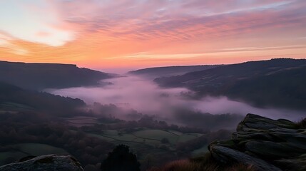 Wall Mural - scenic hilltop view overlooking a misty valley at sunrise, with soft pink and orange hues in the sky