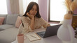 © Krakenimages.com - Young chinese woman using laptop indoors in apartment living room