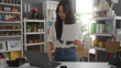 © Krakenimages.com - Young chinese woman in a home decor shop reviewing paperwork by a laptop with various decorative items around