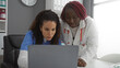 © Krakenimages.com - Women collaborating in healthcare office with diverse backgrounds discussing medical cases indoors using laptop for efficient teamwork.