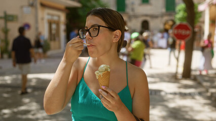 Wall Mural - Young hispanic woman enjoying ice cream in the sunny outdoor streets of valldemossa, mallorca, spain.