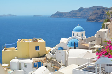 Wall Mural - Oia village on Santorini island, Greece. Traditional and famous houses and churches with blue domes over the Caldera, Cyclades islands Aegean sea.