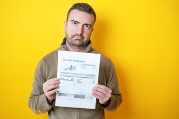 Wall Mural - One man worried about bills reading energy increase costs isolated on yellow background