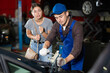 © JackF - Girl watches car mechanic repairing her car in a car service center